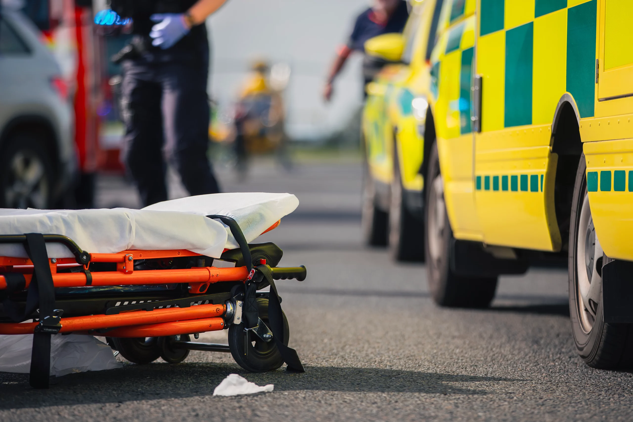 Ambulance scene with folded stretcher and emergency vehicles representing Georgia DUI accident involving death, serious injury, and criminal charges